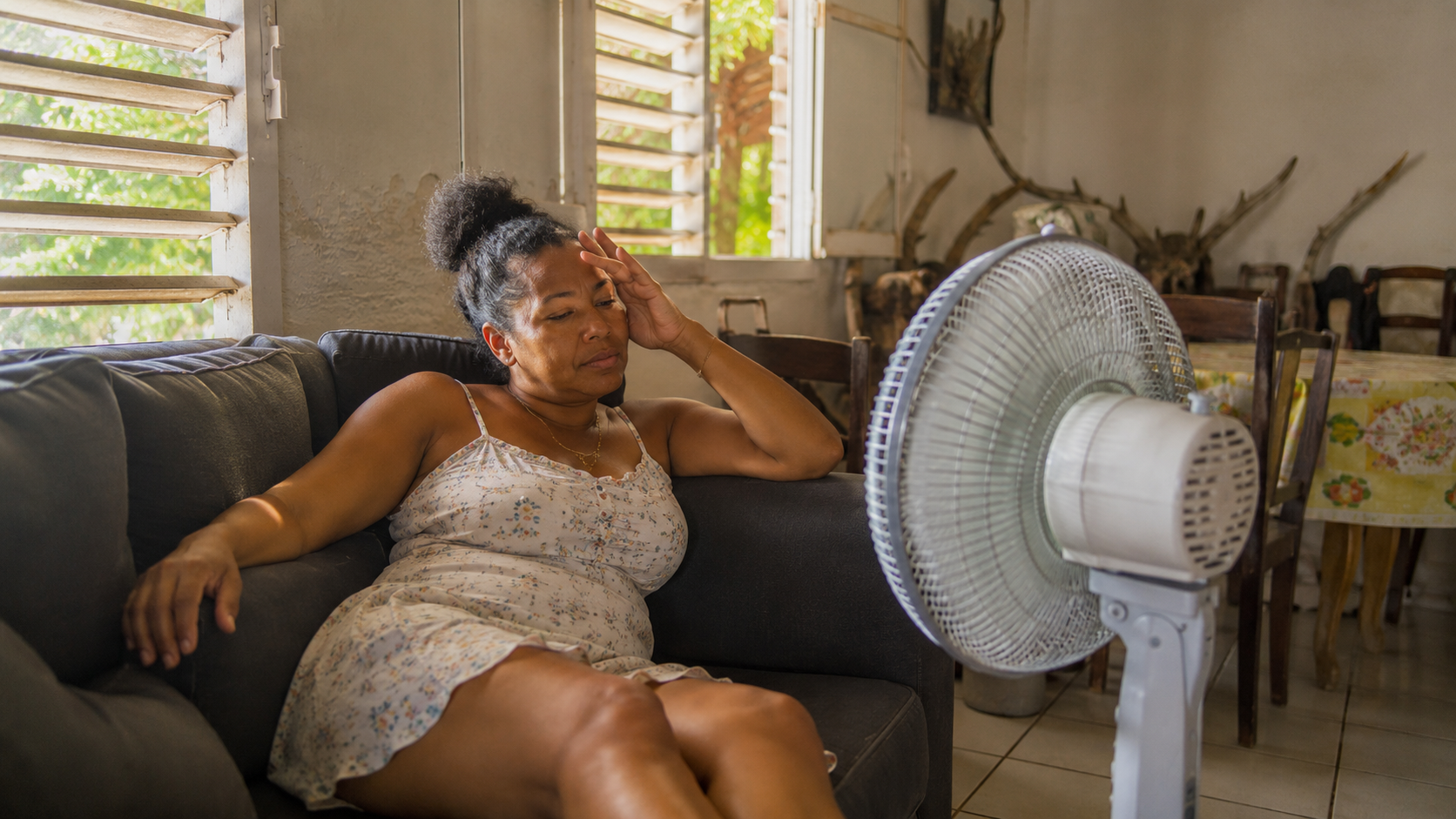 Femme dans son intérieur antillais, ventilateur en marche